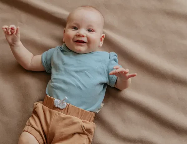 Ein Baby liegt mit Bio-Body im Bett und freut sich