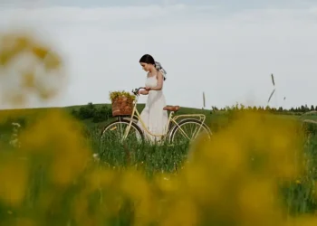 Frau-schiebt-ein-Fahrrad-durch-die-grüne-Wiese-mit-hohem-Gras