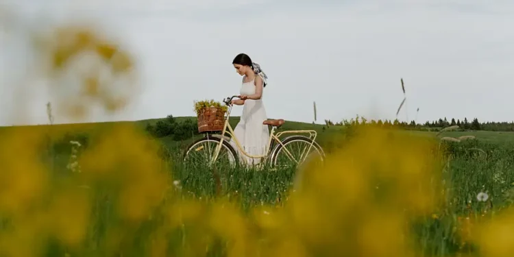 Frau-schiebt-ein-Fahrrad-durch-die-grüne-Wiese-mit-hohem-Gras