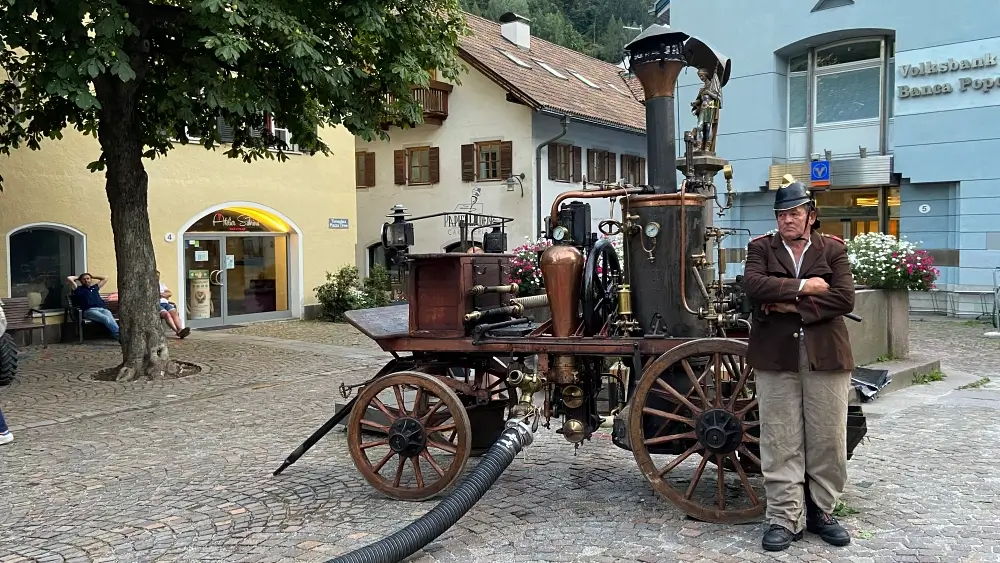 Feuerwehrmann steht vor altem Löschwagen