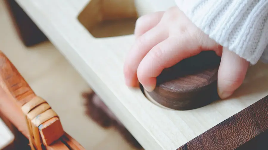 Babyhand in der Kita hält einen Holzklotz in der Hand