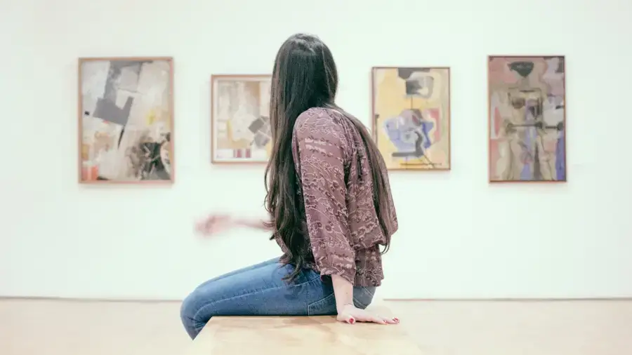 18-Jährige sitzt vor Gemälden, den Eintritt hat sie mit dem Kulturbonus bezahlt